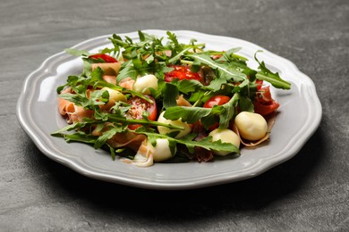 Photo of Tasty salad with arugula on dark textured table, closeup