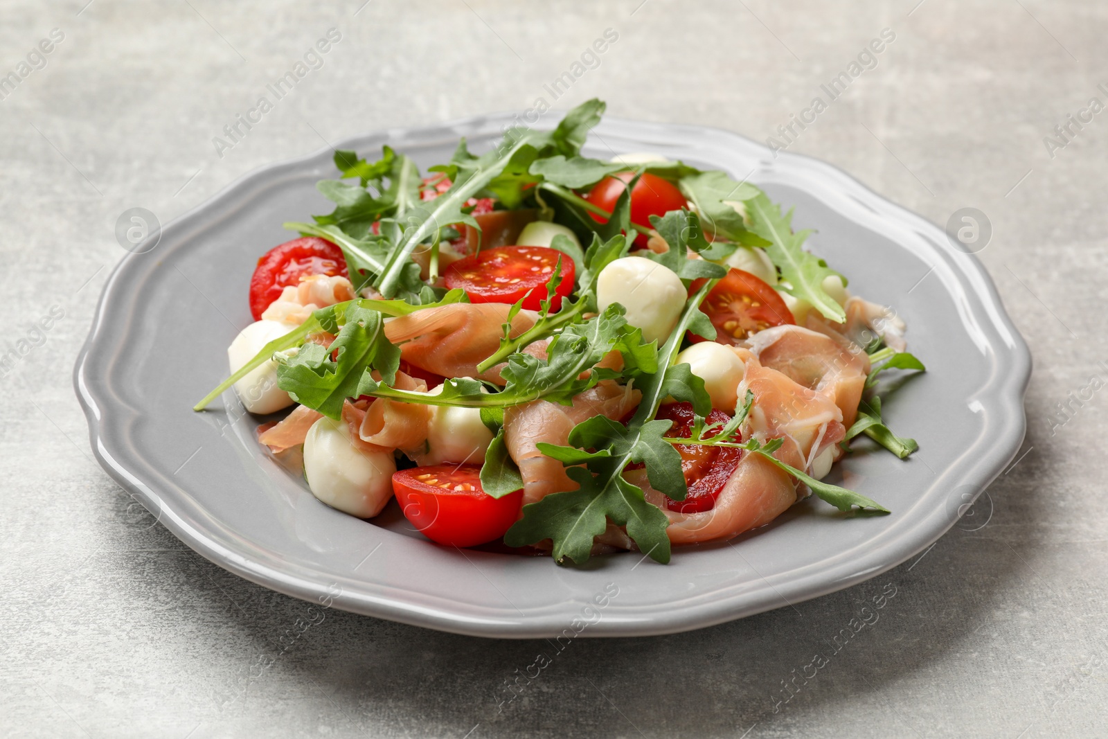 Photo of Tasty salad with arugula on grey textured table, closeup