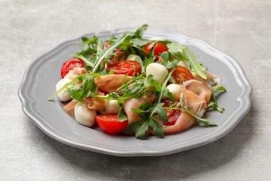 Photo of Tasty salad with arugula on grey textured table, closeup