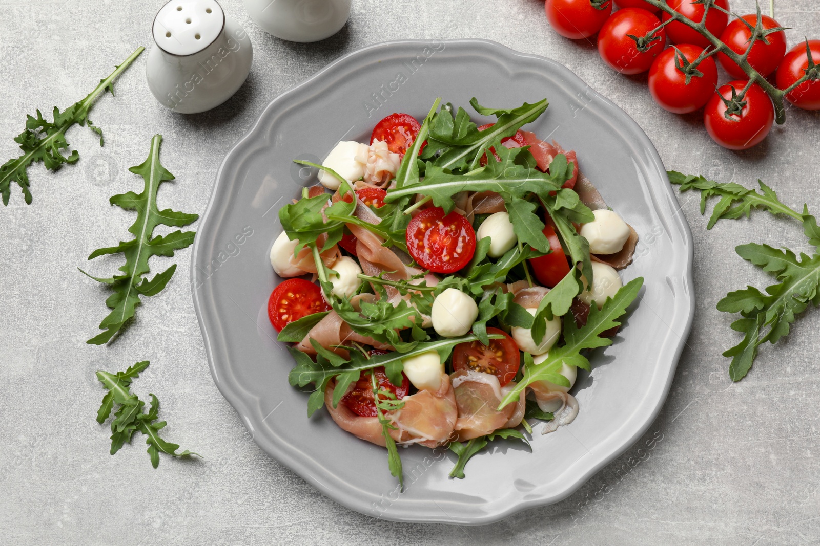 Photo of Tasty salad with arugula on grey textured table, flat lay