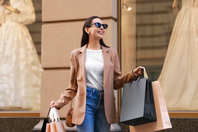 Happy woman with many shopping bags outdoors