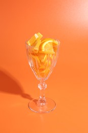 Photo of Orange slices in cocktail glass on orange background