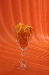 Photo of Orange slices in cocktail glass on orange background