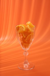 Photo of Orange slices in cocktail glass on orange background