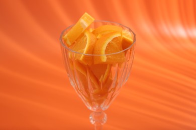 Orange slices in cocktail glass on orange background, closeup