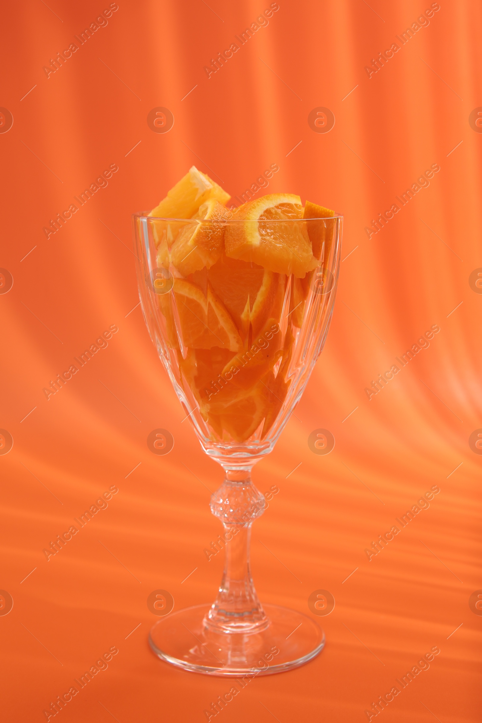 Photo of Orange slices in cocktail glass on orange background