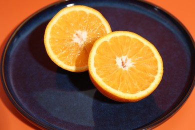 Photo of Halves of orange on dark blue plate, closeup