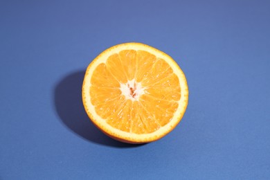 Photo of Half of orange on blue background. Citrus fruit