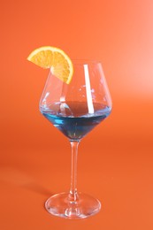 Photo of Blue cocktail in glass on orange background