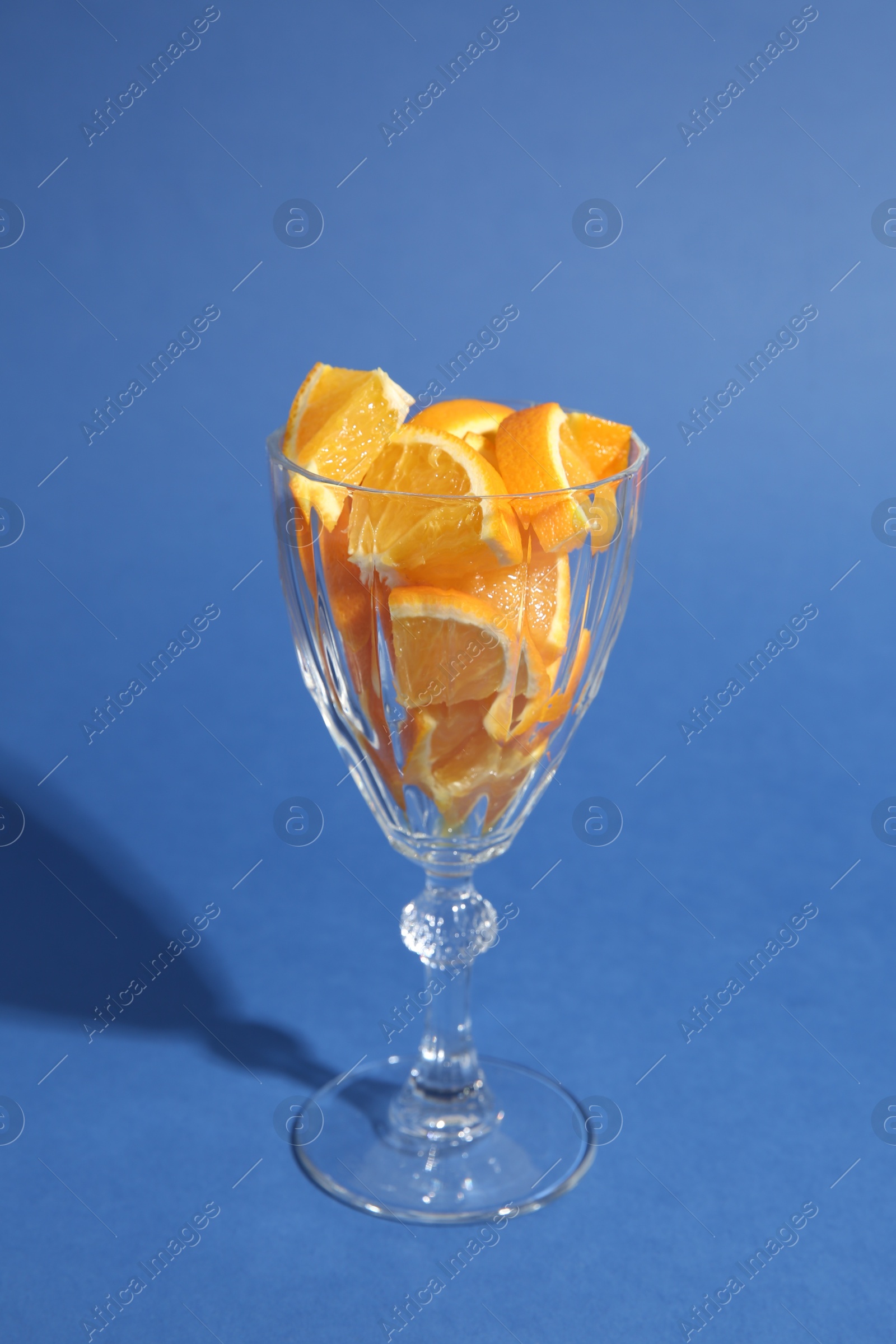 Photo of Orange slices in cocktail glass on blue background