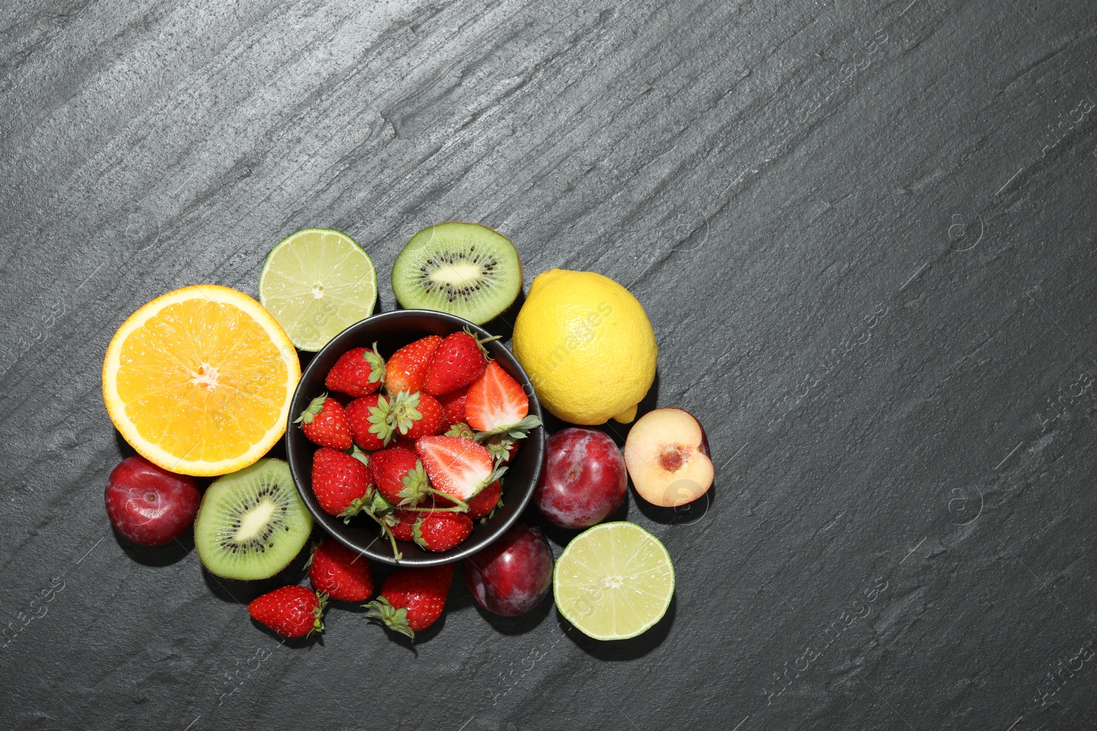 Photo of Different fresh fruits on grey textured table, flat lay. Space for text