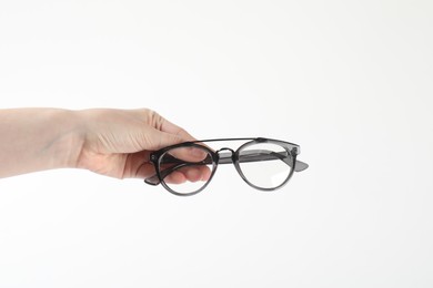 Woman holding glasses with grey frame on white background, closeup