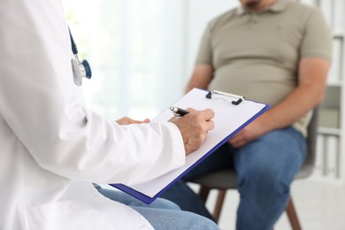 Nutritionist with clipboard consulting overweight man in clinic, closeup