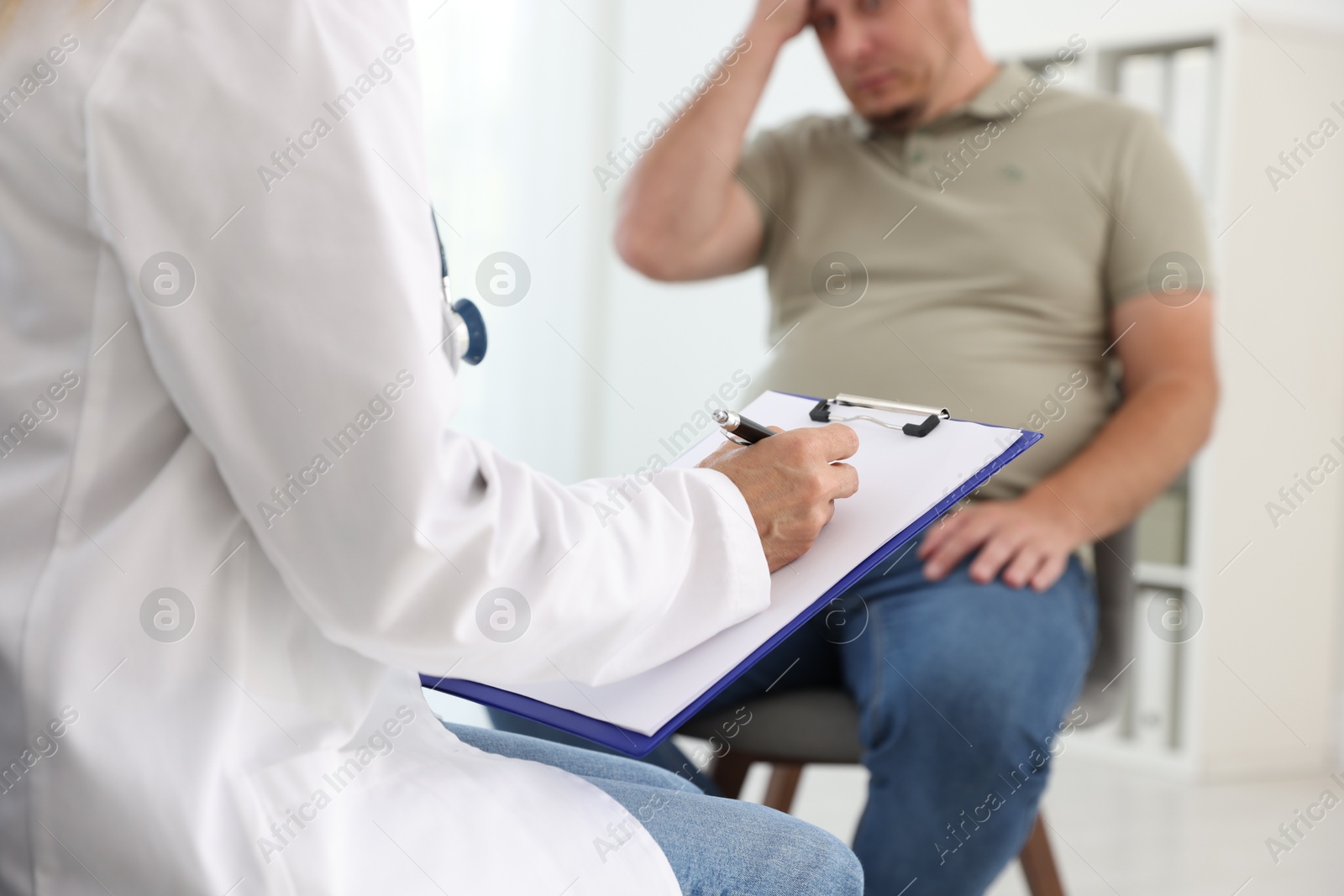 Photo of Nutritionist with clipboard consulting overweight man in clinic, closeup