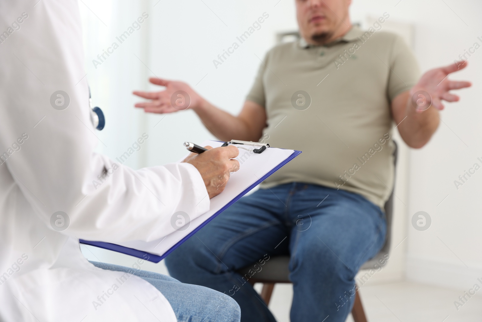 Photo of Nutritionist with clipboard consulting overweight man in clinic, closeup