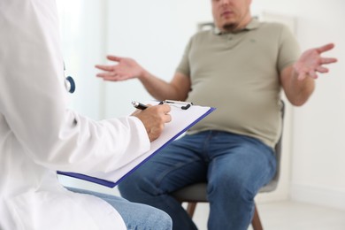 Photo of Nutritionist with clipboard consulting overweight man in clinic, closeup