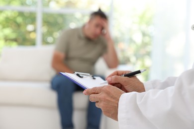 Overweight man having consultation with nutritionist in clinic, selective focus