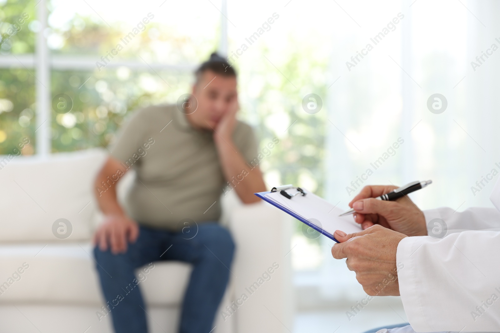 Photo of Overweight man having consultation with nutritionist in clinic, selective focus