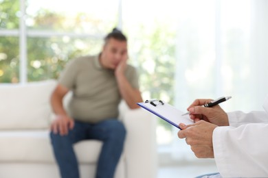 Overweight man having consultation with nutritionist in clinic, selective focus