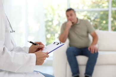 Overweight man having consultation with nutritionist in clinic, selective focus