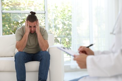 Overweight man having consultation with nutritionist in clinic, selective focus