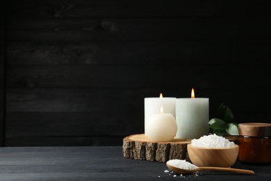 Photo of Composition with cosmetic products and candles for spa treatment on black wooden table, space for text