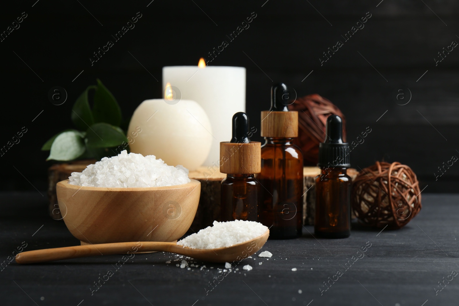 Photo of Composition with cosmetic products and candles for spa treatment on black wooden table, closeup