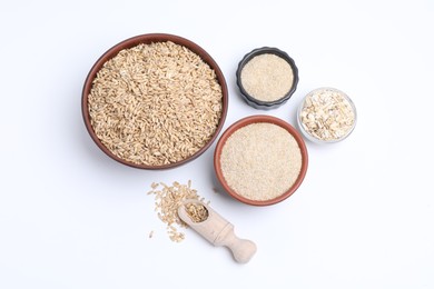 Photo of Oat grains, flakes and bran in bowls isolated on white, top view