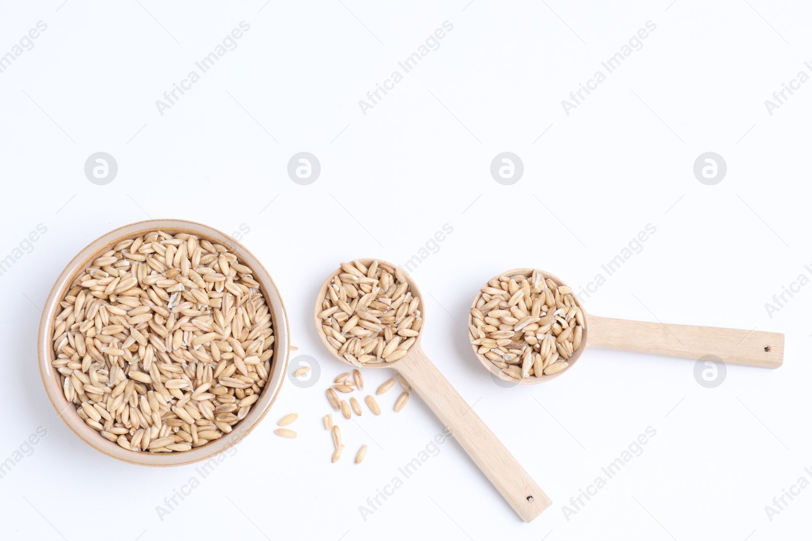 Photo of Oat grains in bowl and spoons isolated on white, top view