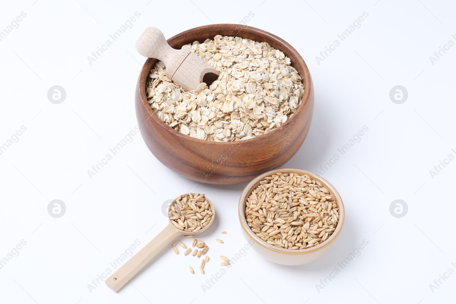 Photo of Oat flakes in bowl, grains, scoop and spoon isolated on white