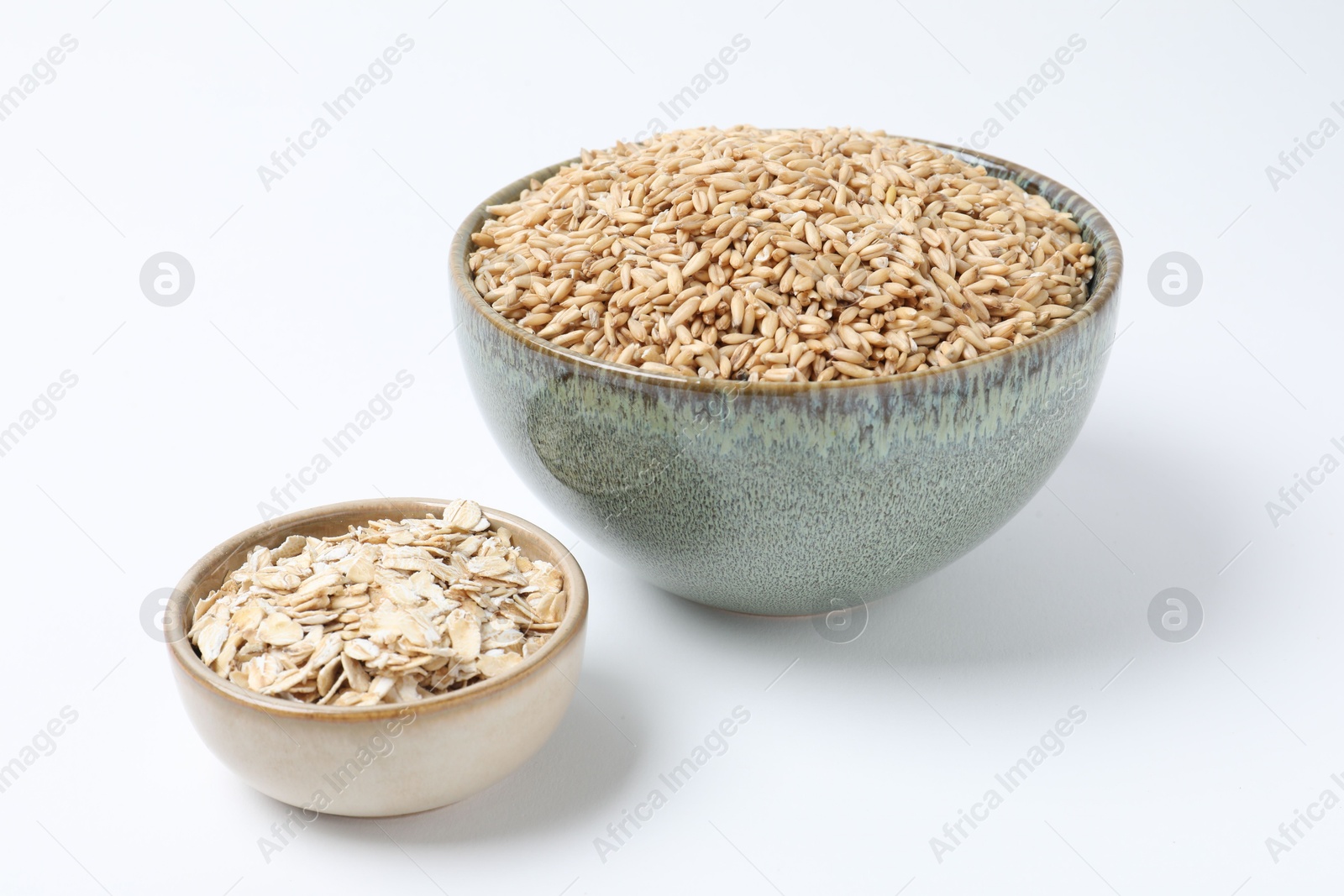 Photo of Oat grains and flakes in bowls isolated on white