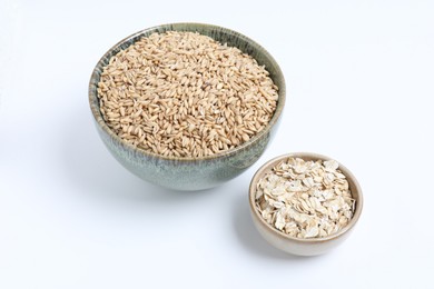 Photo of Oat grains and flakes in bowls isolated on white