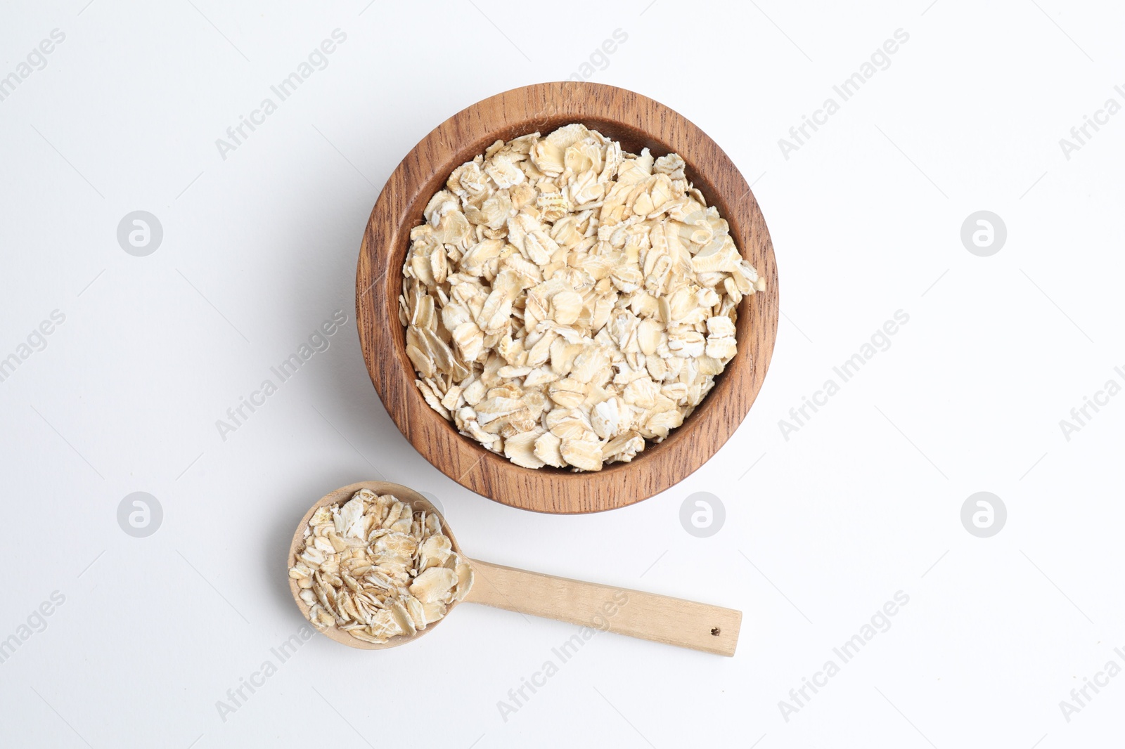 Photo of Oat flakes in bowl and spoon isolated on white, top view