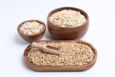 Photo of Oat grains, flakes and bran in dishware isolated on white