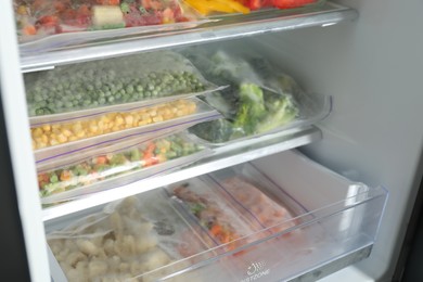 Photo of Plastic bags with different frozen vegetables in refrigerator