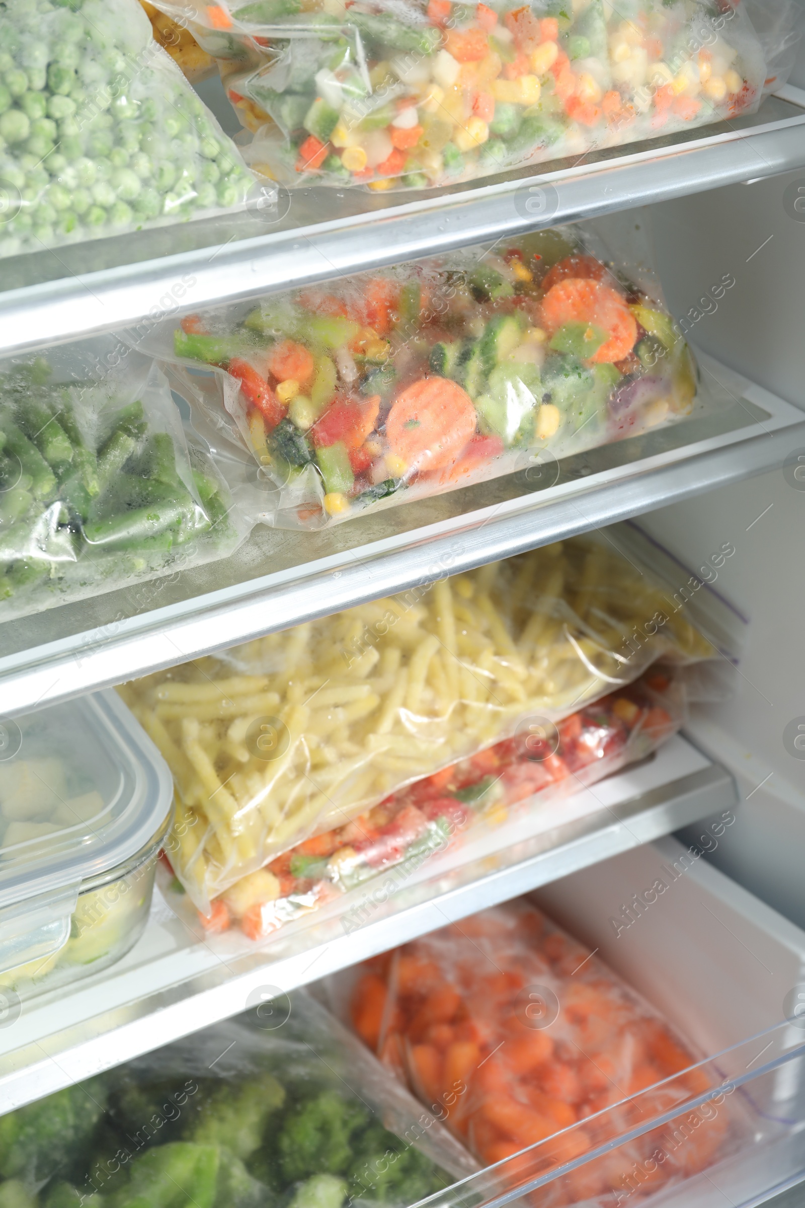 Photo of Plastic bags with different frozen vegetables in refrigerator, closeup