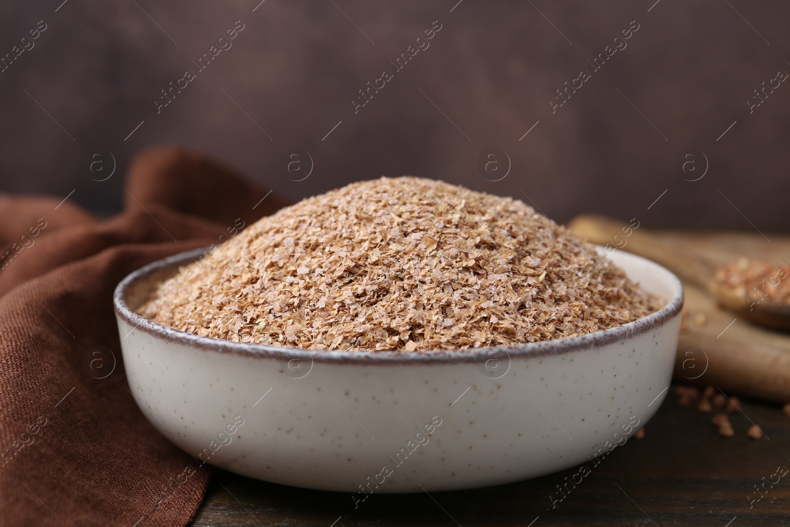 Photo of Buckwheat bran in bowl on wooden table, closeup