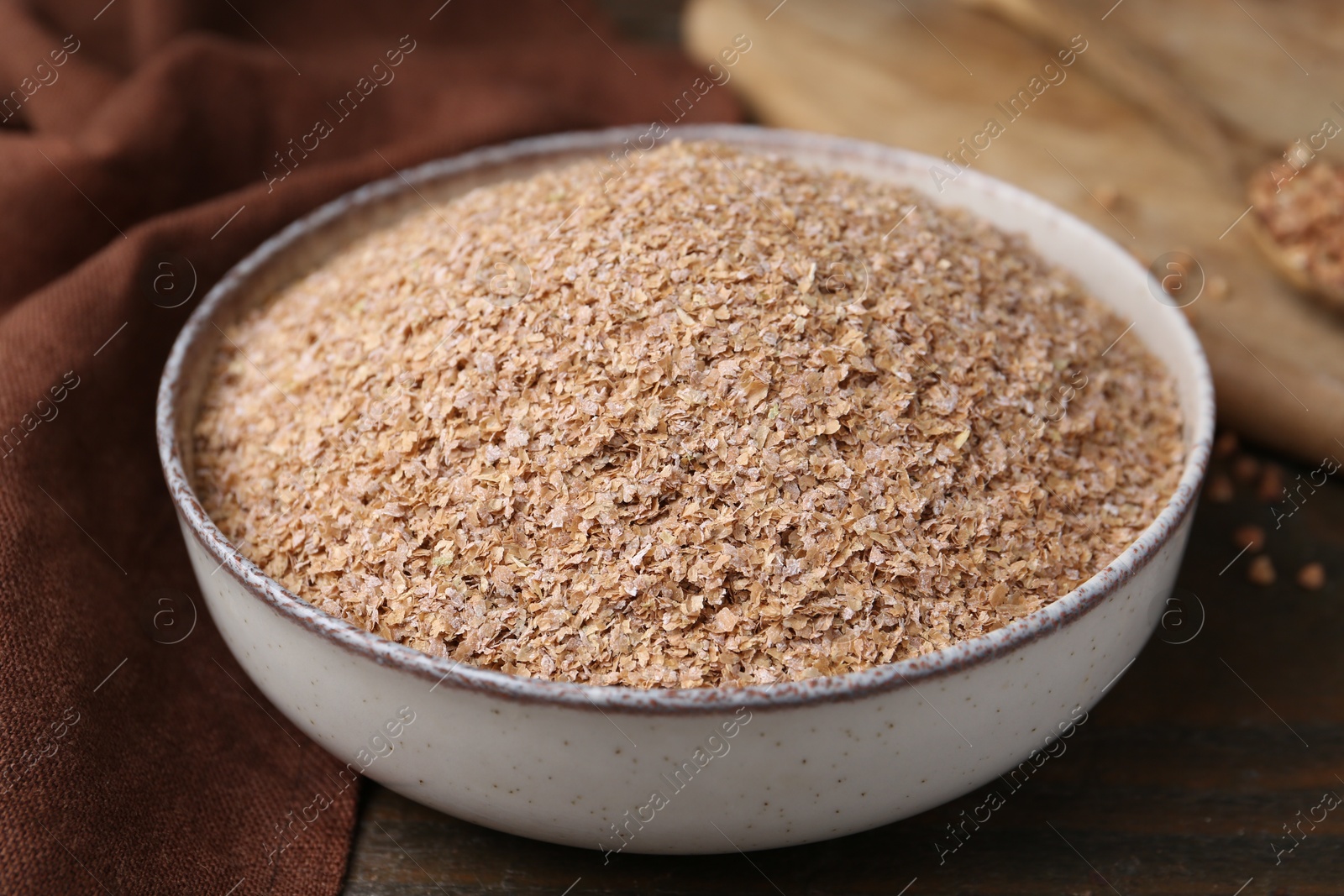 Photo of Buckwheat bran in bowl on wooden table, closeup