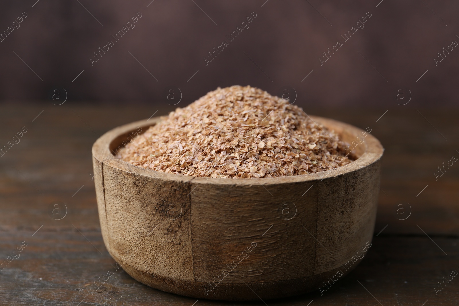 Photo of Buckwheat bran in bowl on wooden table, closeup