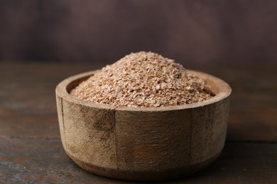 Photo of Buckwheat bran in bowl on wooden table, closeup