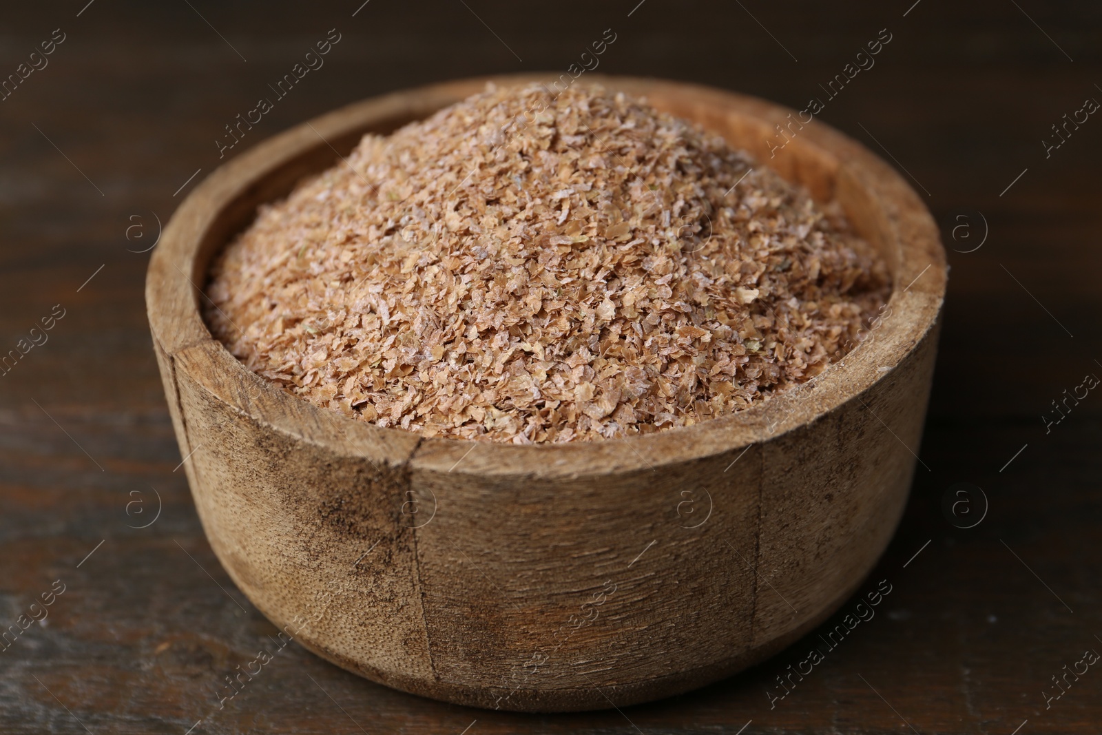 Photo of Buckwheat bran in bowl on wooden table, closeup