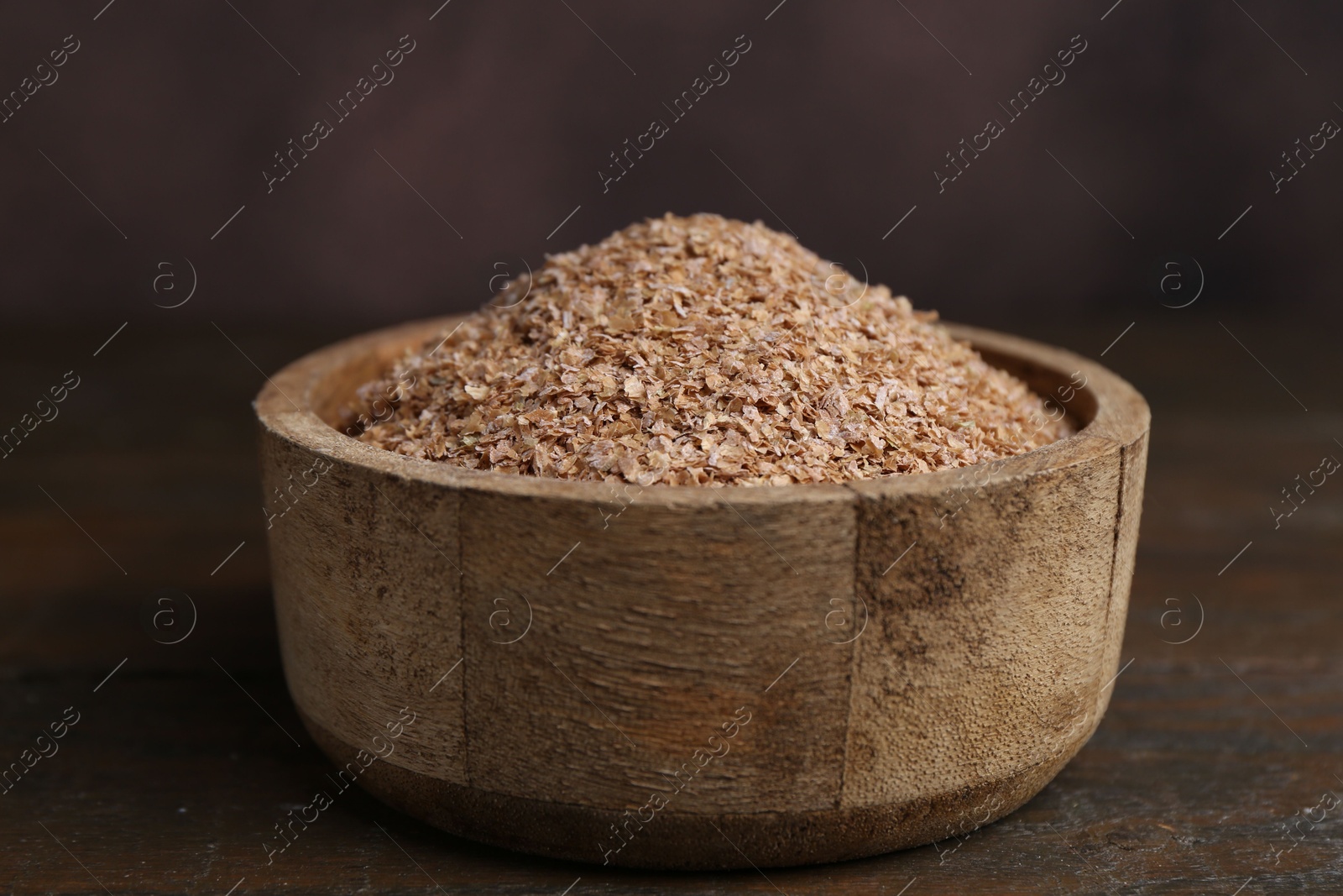 Photo of Buckwheat bran in bowl on wooden table, closeup