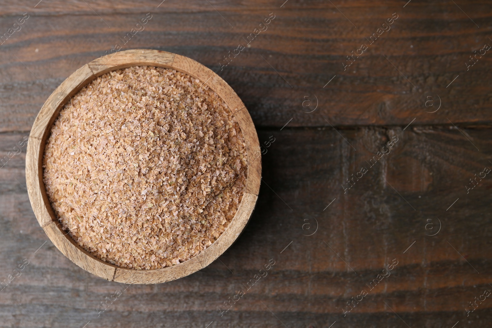 Photo of Buckwheat bran in bowl on wooden table, top view. Space for text