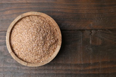 Photo of Buckwheat bran in bowl on wooden table, top view. Space for text