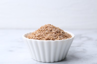 Photo of Buckwheat bran in bowl on white marble table, closeup