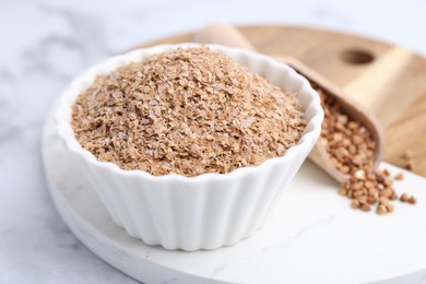 Photo of Buckwheat bran in bowl on white table, closeup