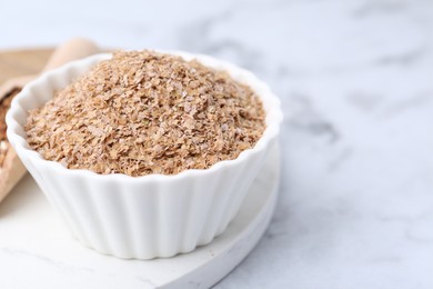 Photo of Buckwheat bran in bowl on white marble table, closeup. Space for text