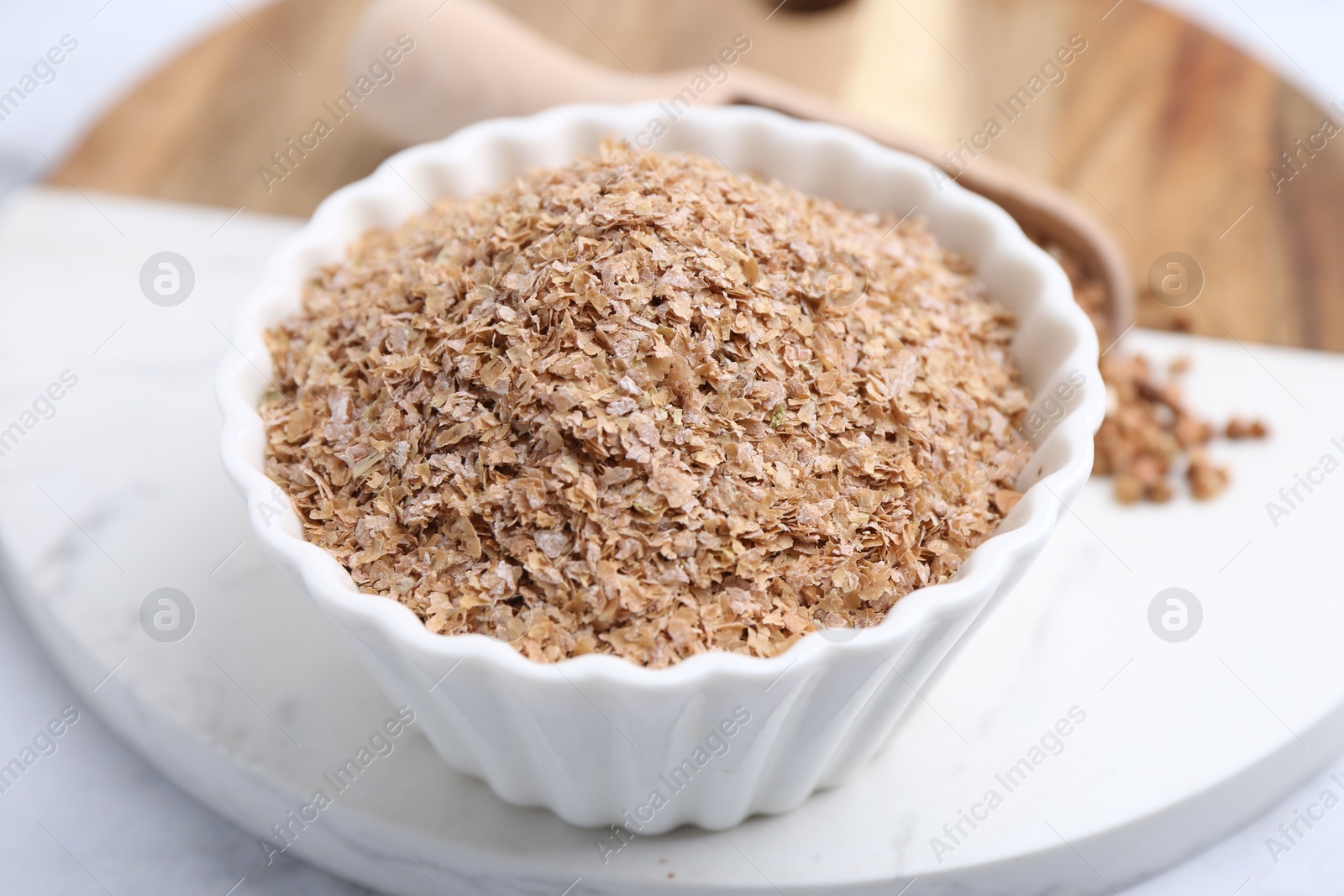 Photo of Buckwheat bran in bowl on white table, closeup