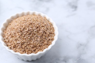 Buckwheat bran in bowl on white marble table, closeup. Space for text