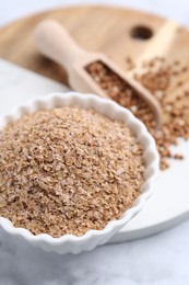 Photo of Buckwheat bran in bowl on white marble table, closeup